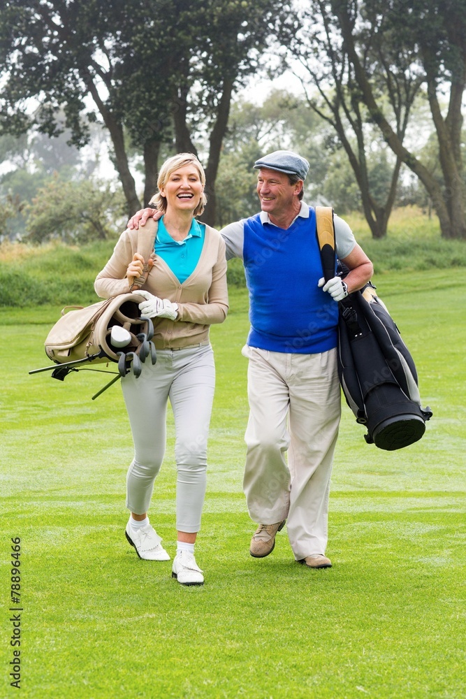 Golfing couple smiling at each other on the putting green Golfing couple smiling at each other on the putting green