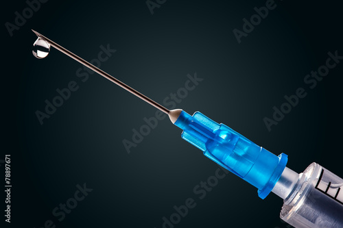Medical syringe with a needle at the end of the drop photo