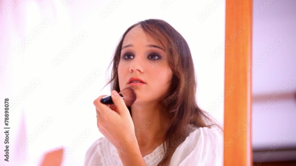 Beautiful young girl paints lips powder preens near the mirror Beautiful young girl paints lips powder preens near the mirror
