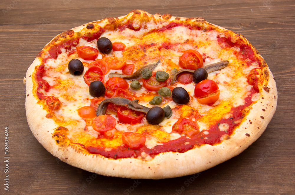 Pizza with anchovies and olives on wooden table