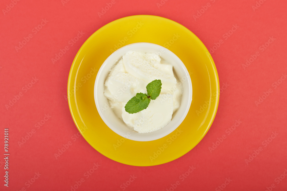 White ice cream in a bowl with mint on a red background White ice cream in a bowl with mint on a red background