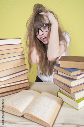 Girl sitting with lots of books and grabs his head..