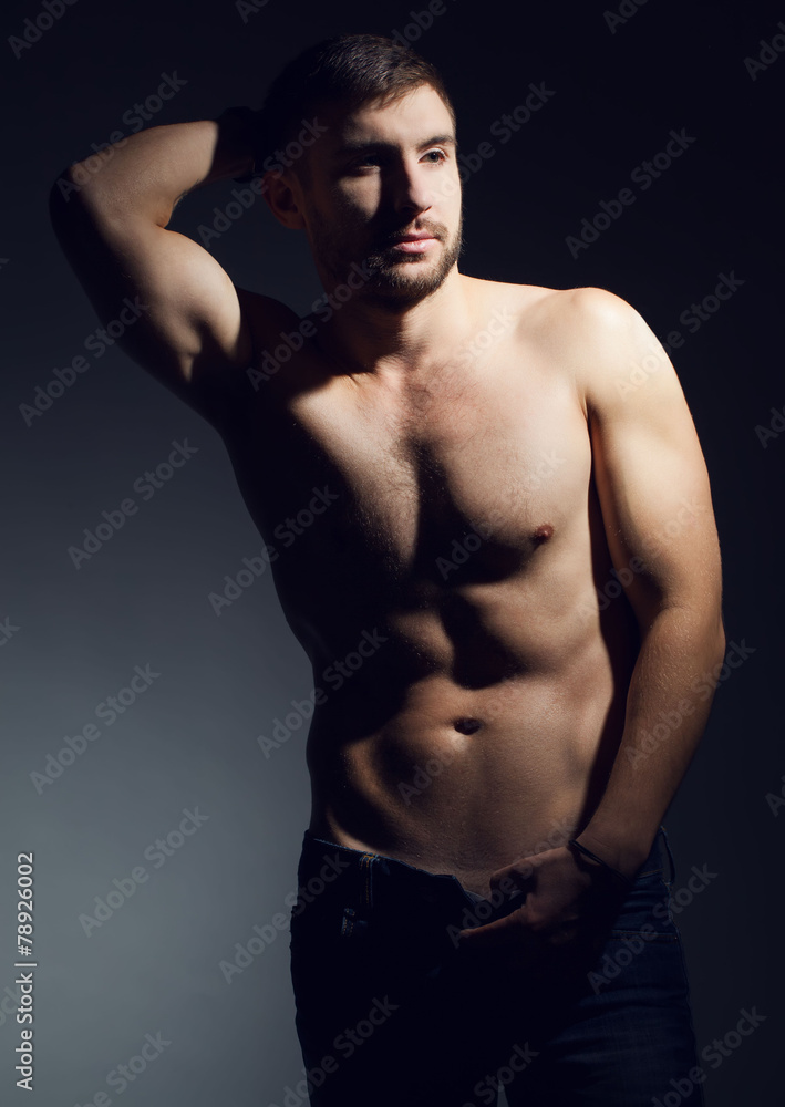 Fototapeta premium Portrait of nude muscular fitness male model in jeans.