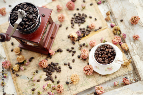 Coffee beans and dried roses scattered upon the old map