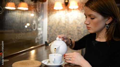 Young girl drinking tea in the evening bar, restaurant, cafe