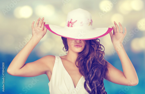 Elegant woman in a white hat on the beach.