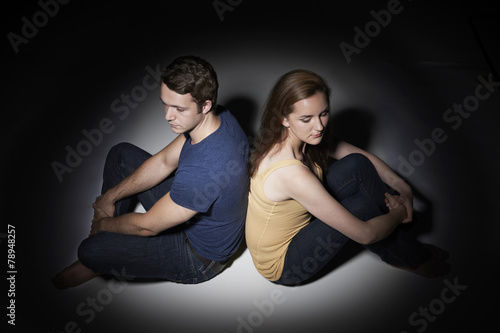 Unhappy Young Couple Sitting In Pool Of Light