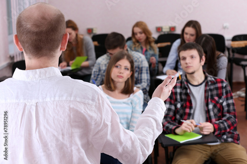 Group of students sitting in classroom and listening teacher