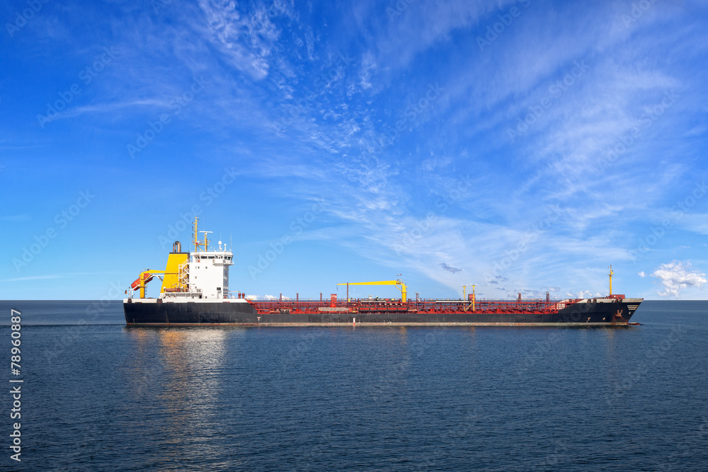 Oil tanker ship at sea on a background of blue sky.