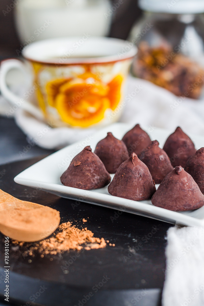 chocolate truffles, cocoa powder in a wooden spoon chocolate truffles, cocoa powder in a wooden spoon