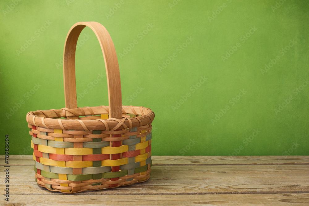 Fototapeta premium Empty basket on wooden table over grunge green background