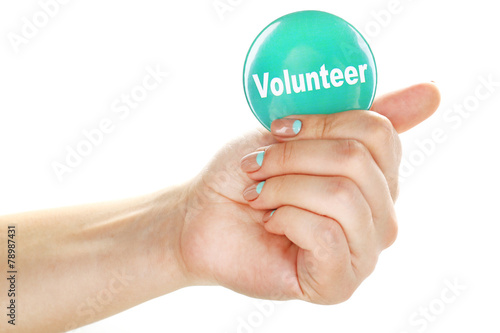 Round volunteer button in hand isolated on white
