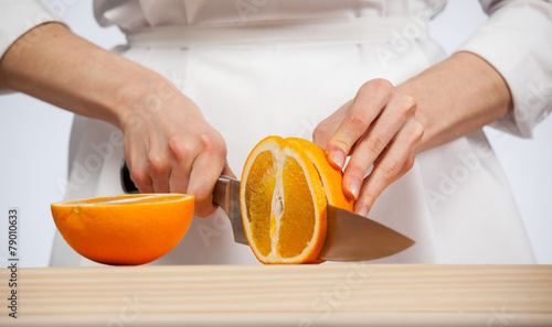 Female hands cutting fresh juicy orange