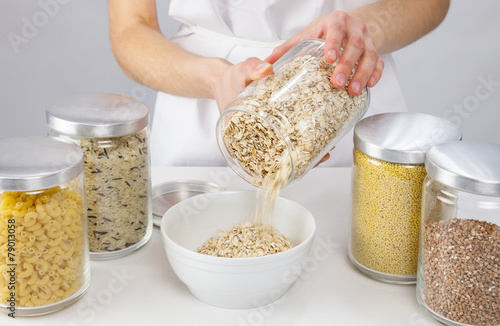 Female hands holding a pot with raw oatmeal