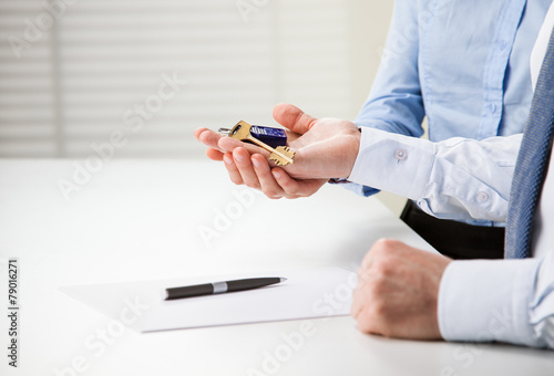 Man and woman hands holding keys from a new house over the table