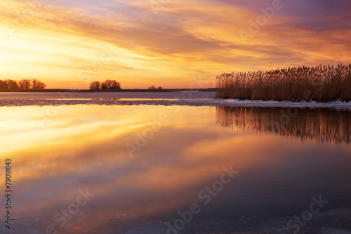 Winter landscape with river  reeds and sunset sky.