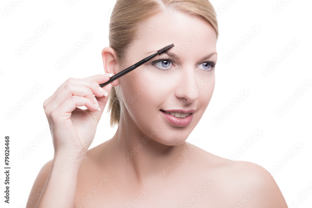 Eine junge Frau mit Mascarabürste trägt Make-Up auf