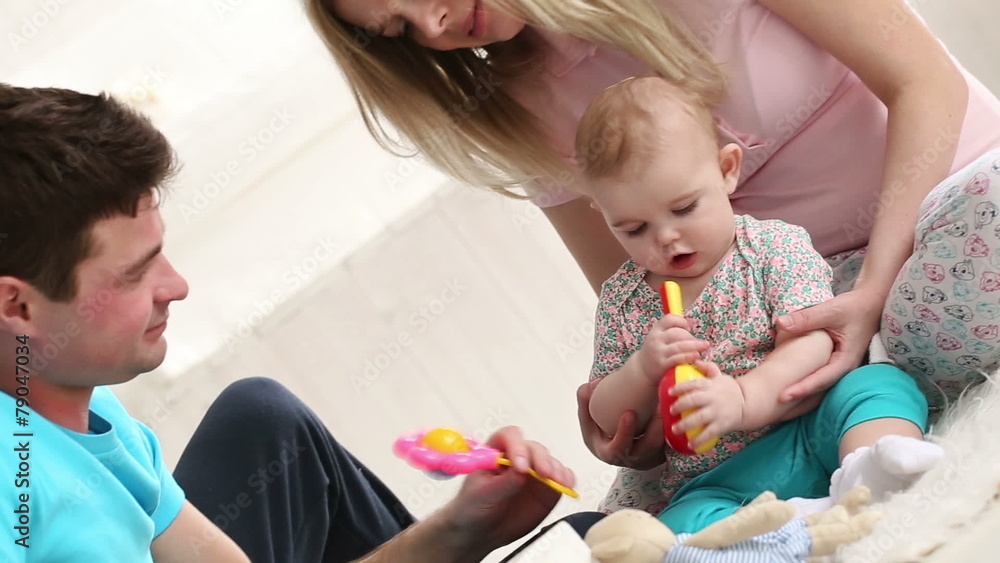young parents playing with the baby at home on the floor young parents playing with the baby at home on the floor