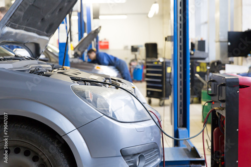 Servicing car air conditioner in auto repair workshop
