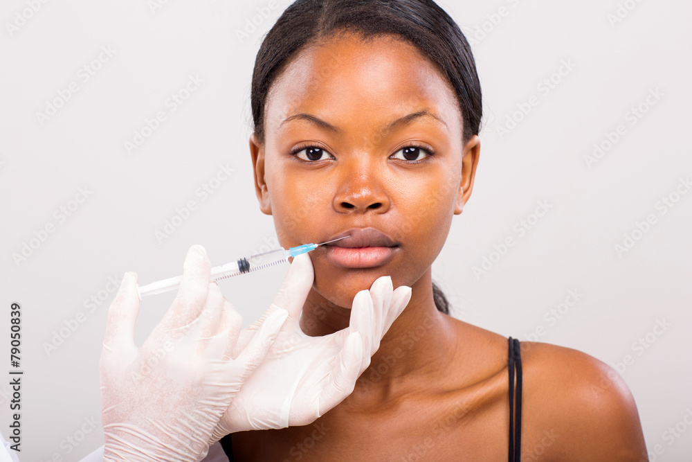 young african woman receiving cosmetic injection in lips young african woman receiving cosmetic injection in lips