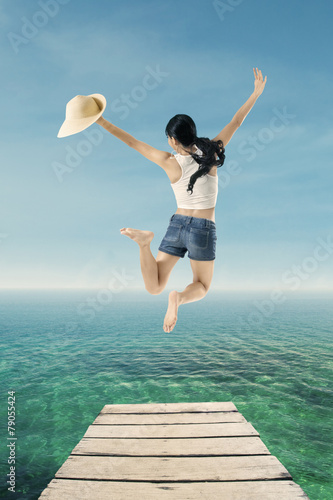 Young woman jumping at pier