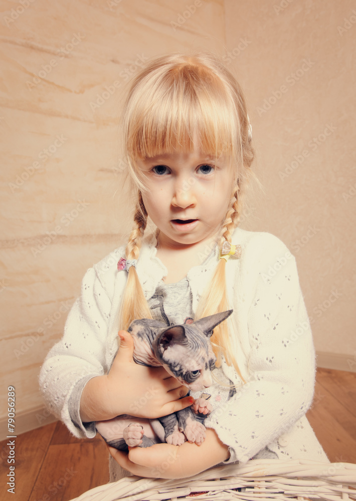 Obraz premium Cute little girl cuddling a small sphynx kitten