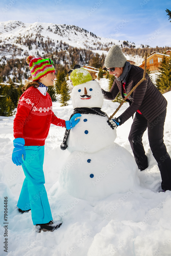 Winter fun, happy family playing with snowman