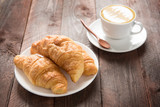 Fresh baked croissants and coffee on wood table