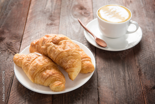 Fresh baked croissants and coffee on wood table