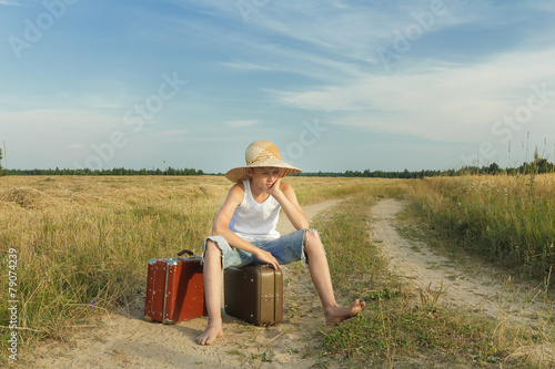 Teenage traveler waiting and sitting on luggage