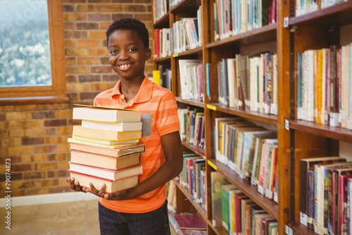 Portrait of cute boy carrying books in library