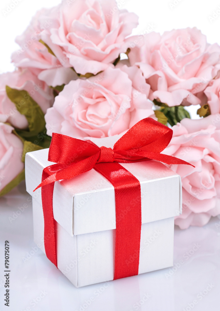 pink flowers and gift box with red ribbon and bow on a white ba pink flowers and gift box with red ribbon and bow on a white ba