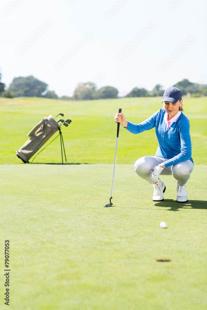 Obraz premium Female golfer watching her ball on putting green