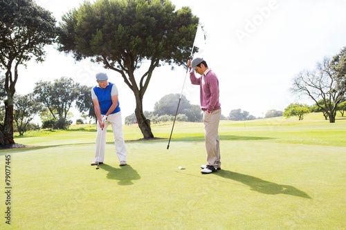 Golfer swinging his club with friend