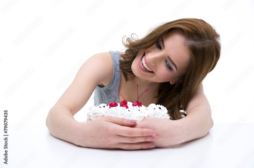 Smiling woman sitting at the table and hugging cake Smiling woman sitting at the table and hugging cake