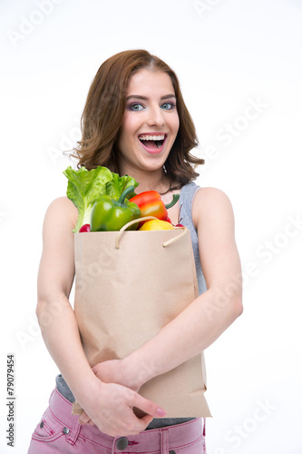 Laughing woman holding a shopping bag full of groceries