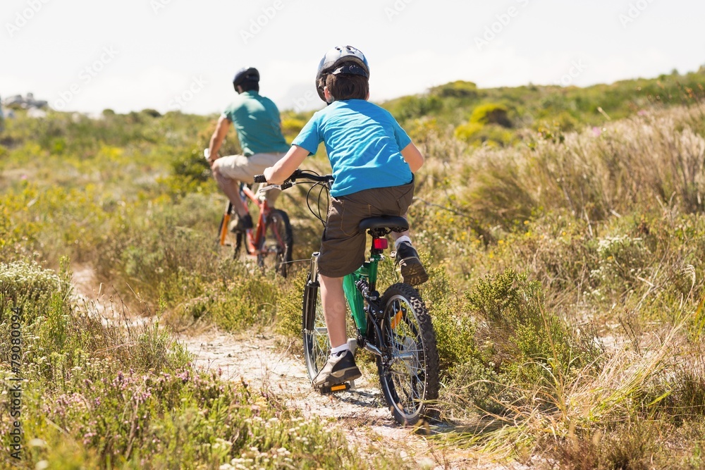 Fototapeta premium Father and son biking through mountains