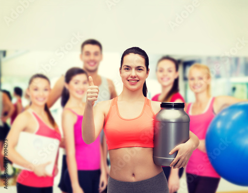 teenage girl with jar of protein showing thumbs up