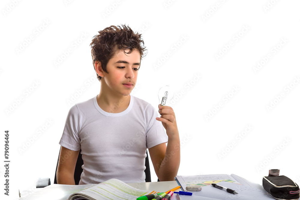 Boy holds a light bulb while doing homework Boy holds a light bulb while doing homework