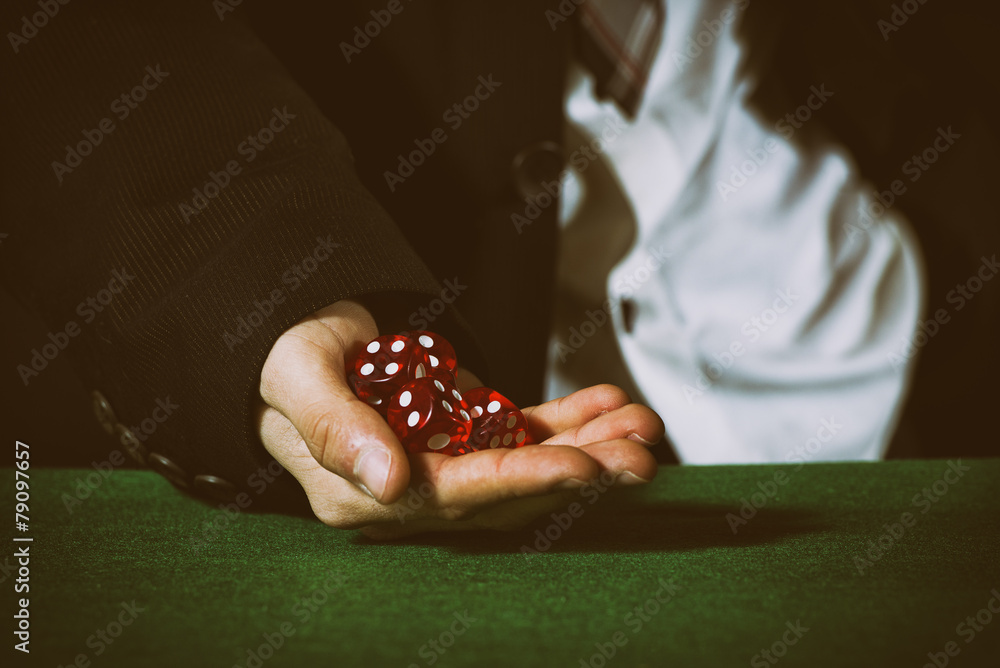 Male hand rolling five dice on green felt