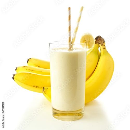 Banana smoothie in a glass with straws over white
