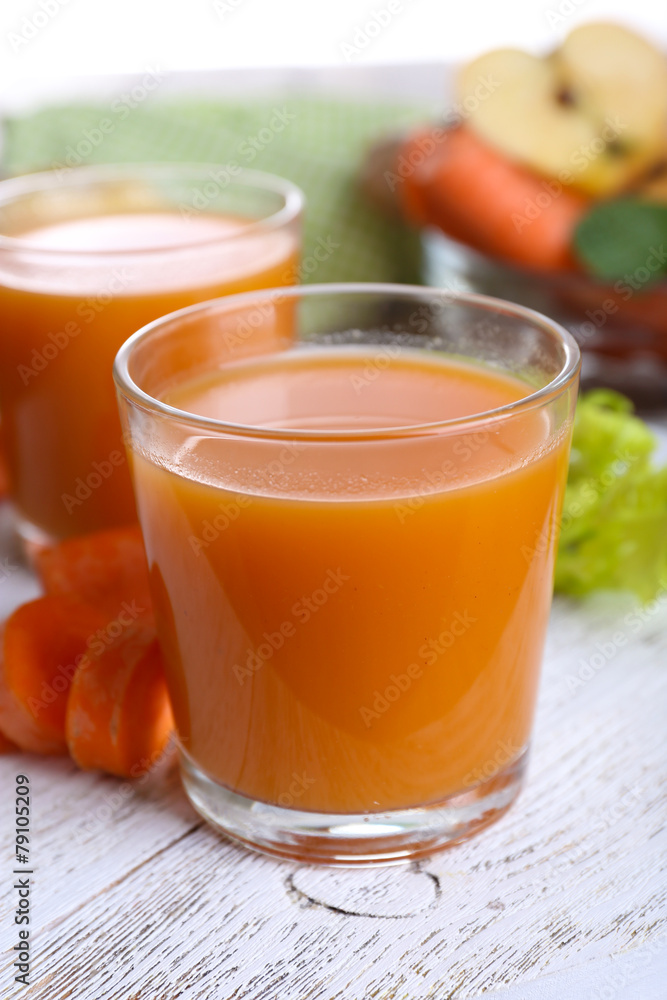 Glasses of juice with apple and carrot on wooden table close up Glasses of juice with apple and carrot on wooden table close up