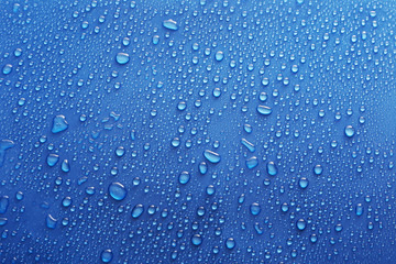Water drops on glass on blue background