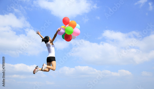 young asian woman mountain peak jumping with colored balloons 