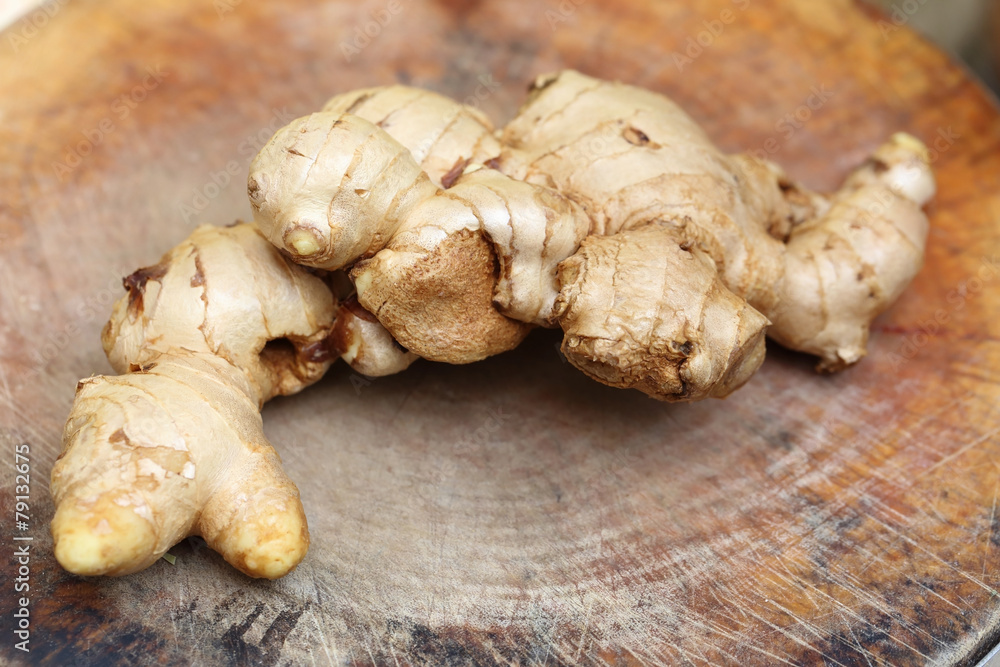 fresh ginger root on wooden chopping block.