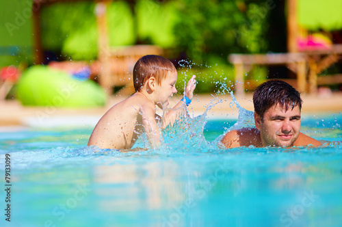 father and son having fun in pool, summer vacation