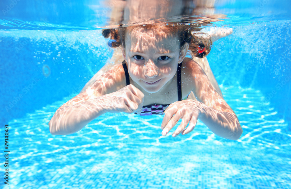 Naklejka premium Happy girl swims in pool underwater, active kid swimming