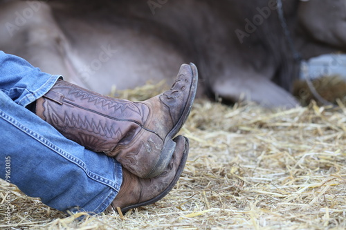 Fotografie tired cowboy in the barn of the farm and a cow in the background