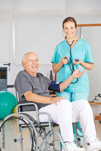 Krankenschwester misst Blutdruck bei Mann im Rollstuhl