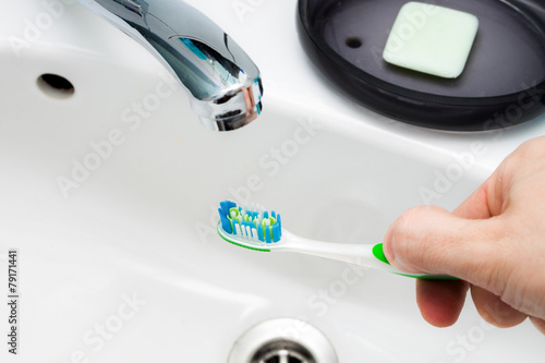 Toothbrush in hand in the bathroom sink